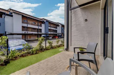 an apartment patio with a lawn and a building at GroundEazy beside Mall of Africa in Midrand