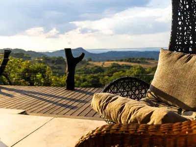a wicker chair with a pillow sitting on a deck at Oluchi Lodge in Guthrie