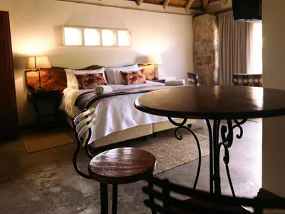 a bedroom with a bed and a table and chairs at Oluchi Lodge in Guthrie