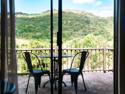 a table and chairs on a balcony with a view of a mountain at Oluchi Lodge in Guthrie