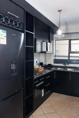 a kitchen with black cabinets and a black refrigerator at Pamuzinda Airbnb at Urban Cove in Nelspruit