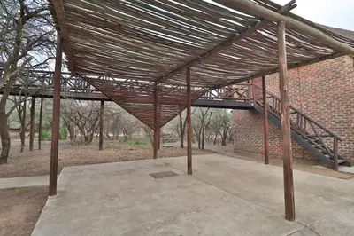 a large wooden pavilion with a staircase in a brick building at Lion Den in Marloth Park