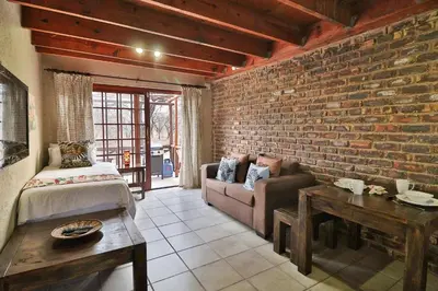 a living room with a brick wall and a couch at Lion Den in Marloth Park