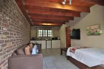 a bedroom with a bed and a brick wall at Lion Den in Marloth Park