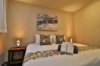 a bedroom with a large white bed with pillows at Lion Den in Marloth Park