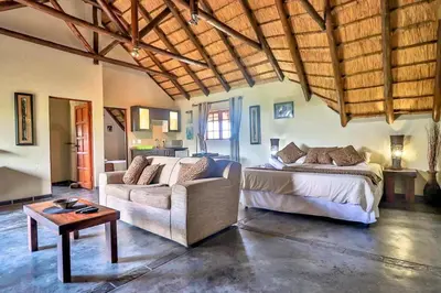 a bedroom with a bed and a couch and a table at Leopard Chalet - Solar System in Marloth Park
