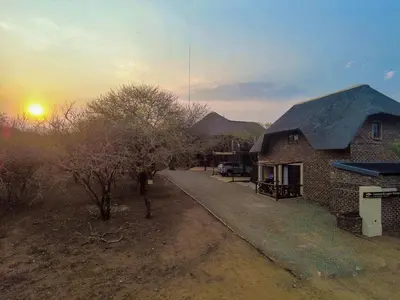 a brick house with a sunset in the background at Leopard Chalet - Solar System in Marloth Park