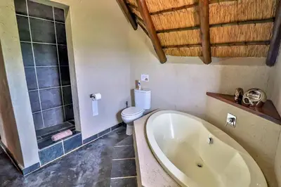 a bathroom with a bath tub and a toilet at Leopard Chalet - Solar System in Marloth Park