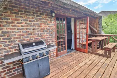 a brick house with a grill on a wooden deck at Leopard Chalet - Solar System in Marloth Park