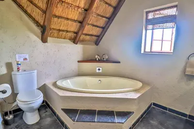 a bathroom with a large tub and a toilet at Leopard Chalet - Solar System in Marloth Park