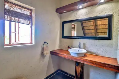 a bathroom with a sink and a mirror at Leopard Chalet - Solar System in Marloth Park