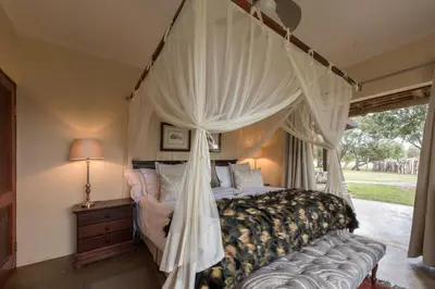 a bedroom with a canopy bed and a lamp at Tintswalo Safari in Manyeleti Game Reserve