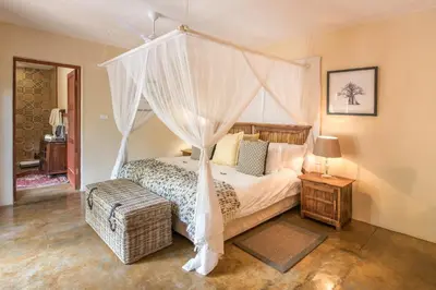 a bedroom with a canopy bed with a wicker ottoman and a table at Tintswalo Safari in Manyeleti Game Reserve