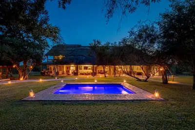 a swimming pool in the yard of a house at night at Tintswalo Safari in Manyeleti Game Reserve