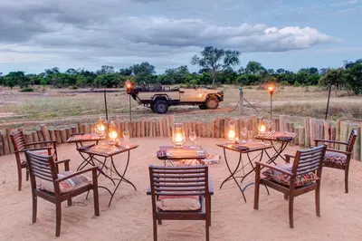 a group of tables and chairs with a jeep in the background at Tintswalo Safari in Manyeleti Game Reserve