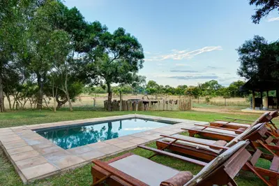 a swimming pool with chairs and a picnic table at Tintswalo Safari in Manyeleti Game Reserve
