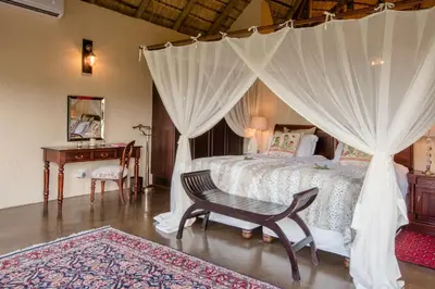 a bedroom with a bed with curtains and a desk at Tintswalo Safari in Manyeleti Game Reserve