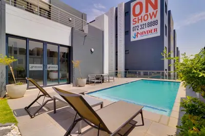 a patio with a swimming pool and chairs and a building at Smartz Apartment312 in Midrand