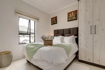 a white bedroom with a large bed and a window at Smartz Apartment312 in Midrand