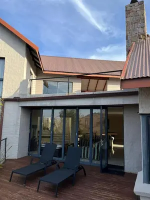 two chairs on a deck in front of a house at Waterfall House in Dullstroom