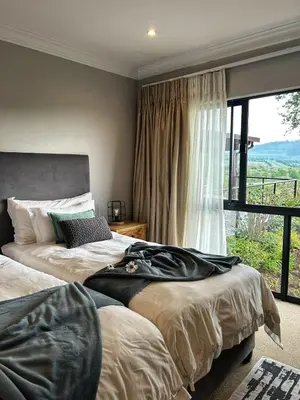 a bedroom with two beds and a large window at Waterfall House in Dullstroom