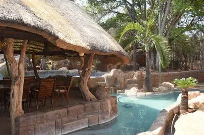 a resort swimming pool with a thatch roof and a restaurant at Golf View Guest House in Musina