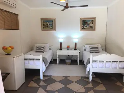 two beds in a room with two tables and two lamps at Golf View Guest House in Musina