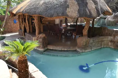 a swimming pool with a hut with a table at Golf View Guest House in Musina