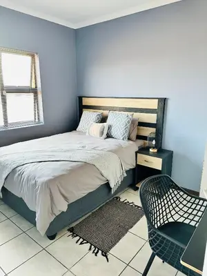a bedroom with a large bed and a chair at Charming Wallet Friendly Apartment in Polokwane
