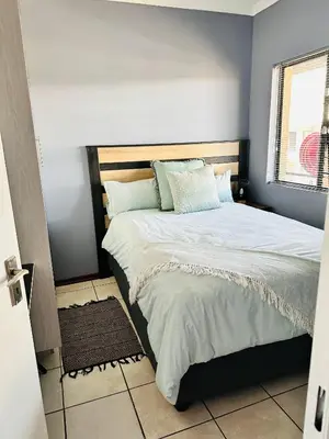 a bedroom with a large bed with white sheets and a window at Charming Wallet Friendly Apartment in Polokwane