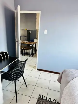 a room with a table and a chair and a kitchen at Charming Wallet Friendly Apartment in Polokwane