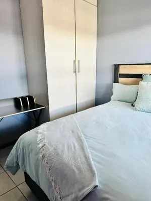 a bedroom with a white bed with a white cabinet at Charming Wallet Friendly Apartment in Polokwane