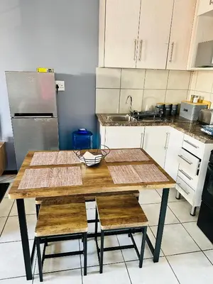 a kitchen with a wooden table with chairs and a sink at Charming Wallet Friendly Apartment in Polokwane