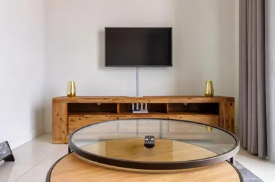 a living room with a tv and a glass table at AlimamaSpaces The Moksit Suite Ellipse in Midrand