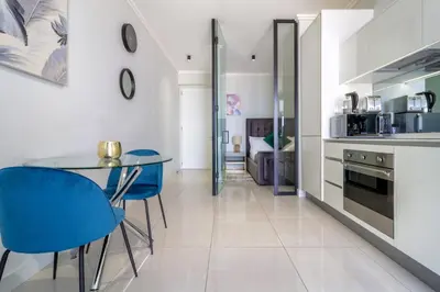 a kitchen with a glass table and blue chairs at AlimamaSpaces The Moksit Suite Ellipse in Midrand