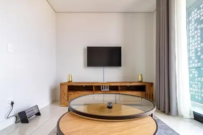 a living room with a table and a tv at AlimamaSpaces The Moksit Suite Ellipse in Midrand
