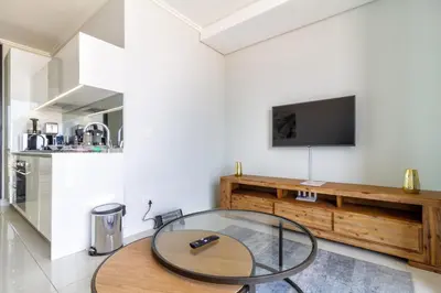 a living room with a glass table and a television at AlimamaSpaces The Moksit Suite Ellipse in Midrand
