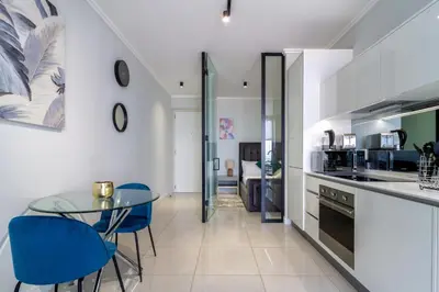 a kitchen with a glass table and blue chairs at AlimamaSpaces The Moksit Suite Ellipse in Midrand