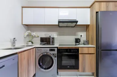 a kitchen with white cabinets and a washer and dryer at Lovely 2 bed @TheBlyde in Pretoria