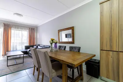 a kitchen and dining room with a wooden table and chairs at Lovely 2 bed @TheBlyde in Pretoria