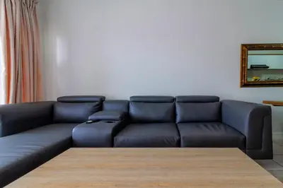 a living room with a black couch and a mirror at Lovely 2 bed @TheBlyde in Pretoria