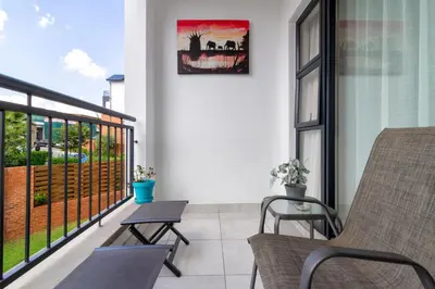 a balcony with two chairs and a table on a building at Lovely 2 bed @TheBlyde in Pretoria