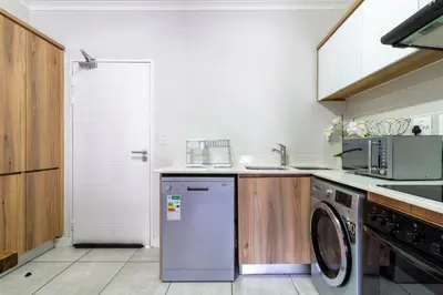 a kitchen with a washing machine and a sink at Lovely 2 bed @TheBlyde in Pretoria