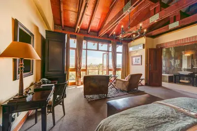a bedroom with a bed and a desk and a table at Riboville Boutique Hotel And Restaurant in Midrand