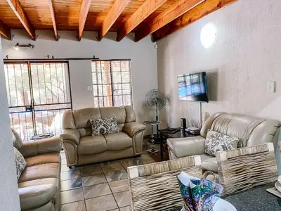 a living room with couches and a flat screen tv at Escape@Butterfly in Marloth Park