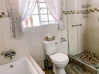 a bathroom with a toilet and a tub and a window at Escape@Butterfly in Marloth Park