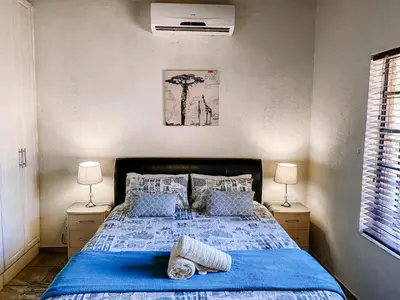 a bedroom with a blue bed with two lamps at Escape@Butterfly in Marloth Park
