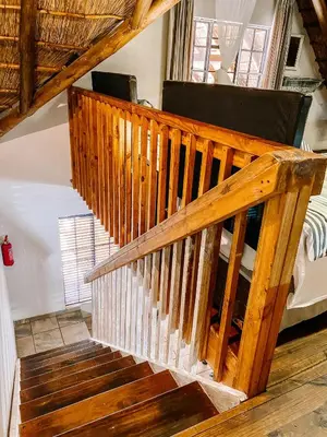 a wooden staircase in a room with a couch at Escape@Butterfly in Marloth Park