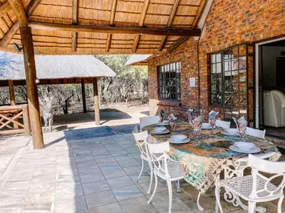 a patio with a table and chairs and a brick building at Escape@Butterfly in Marloth Park