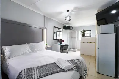 a bedroom with a large white bed and a kitchen at Patimo Opulent Accommodation -Pretoria Mayville,Gezina in Pretoria